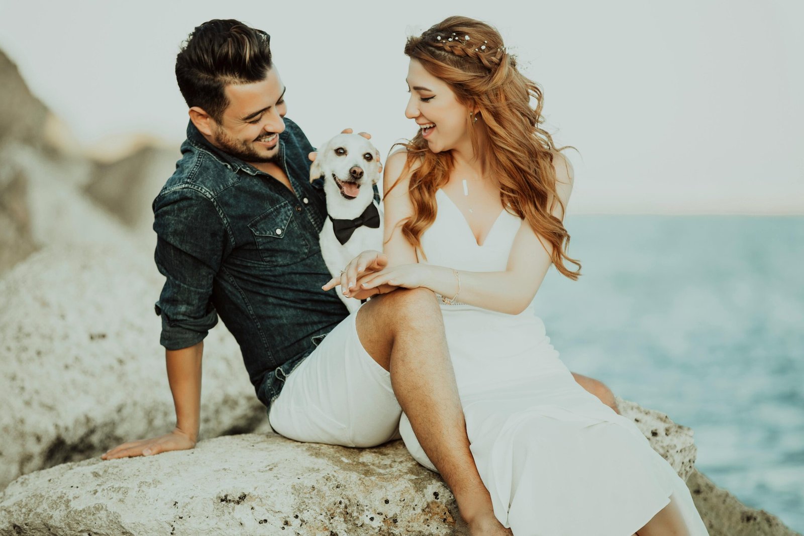 Happy couple with a dog enjoying a seaside moment on a sunny day